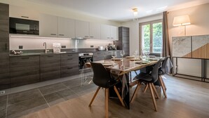 A modern kitchen with dark wood cabinets, a built-in oven, and a dining area with a wooden table and chairs.