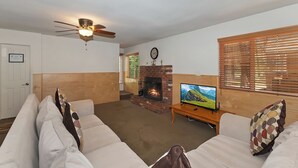 Una sala de estar con chimenea, ventilador de techo y televisión.