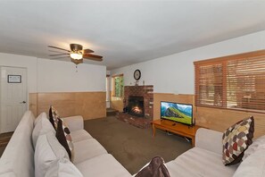 A living room with a fireplace, television, and a ceiling fan.