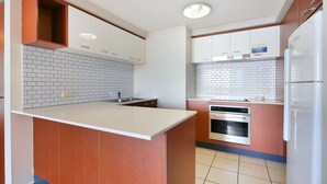 A modern kitchen with white cabinets, a central island, and a built-in oven.