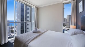 A hotel room with a large bed, a view of the cityscape, and a window with curtains.