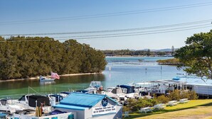 A marina with boats, a restaurant bar, and picnic tables on a grassy area. - Braemar 7 - Lakefront apartment (Forster)