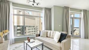 A modern living room with a sofa, a glass coffee table, and large windows offering a city view.