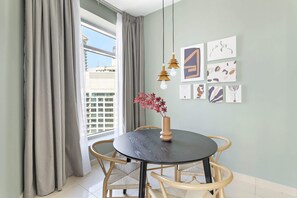 A dining area with a round table, four chairs, a vase with flowers, and wall art.