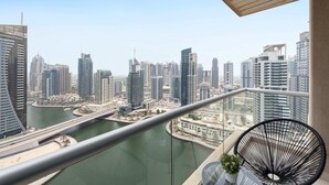 A high-rise balcony with a view of a cityscape, including modern buildings and a river.
