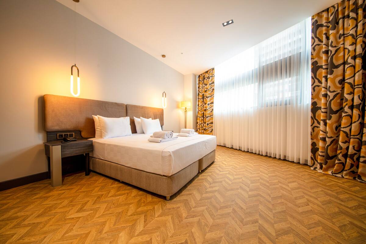 A hotel room with a large bed, a bedside table, and a lamp.