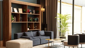 A modern living room with a sectional sofa, a coffee table, and a bookshelf. - V Center Hotel (Yomra)
