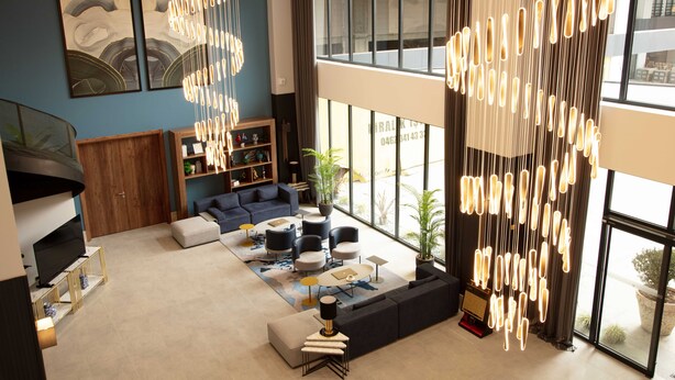 A modern living room with a sofa, coffee table, and a TV. There are curtains, a bookshelf, and a large window. - V Center Hotel (Yomra)