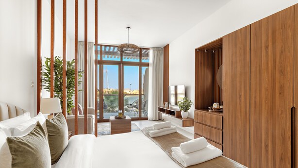 Une chambre moderne avec un grand lit, une armoire en bois et une vue sur l’extérieur.