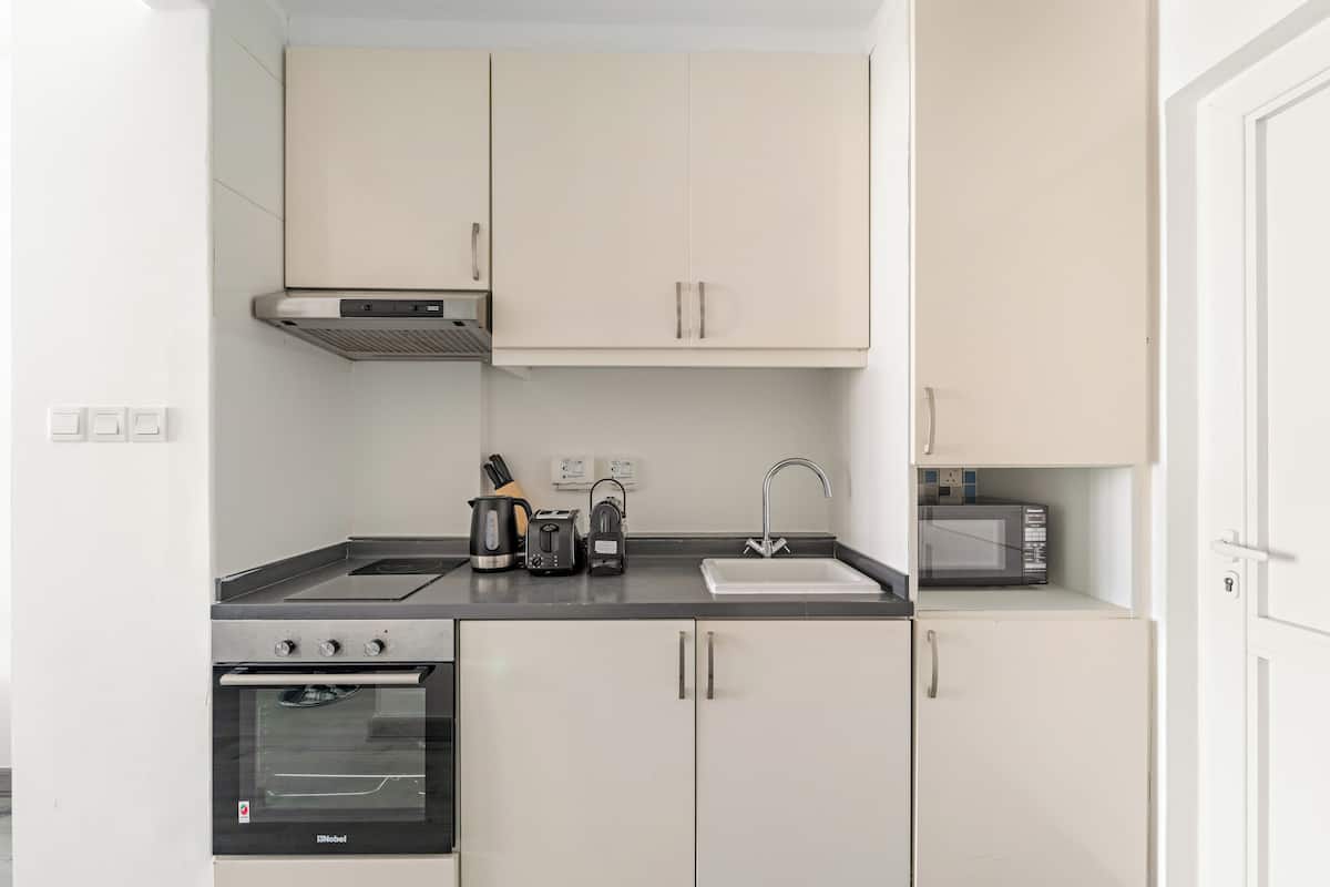 A compact kitchen with a built-in oven, a microwave, a sink, and cabinets.