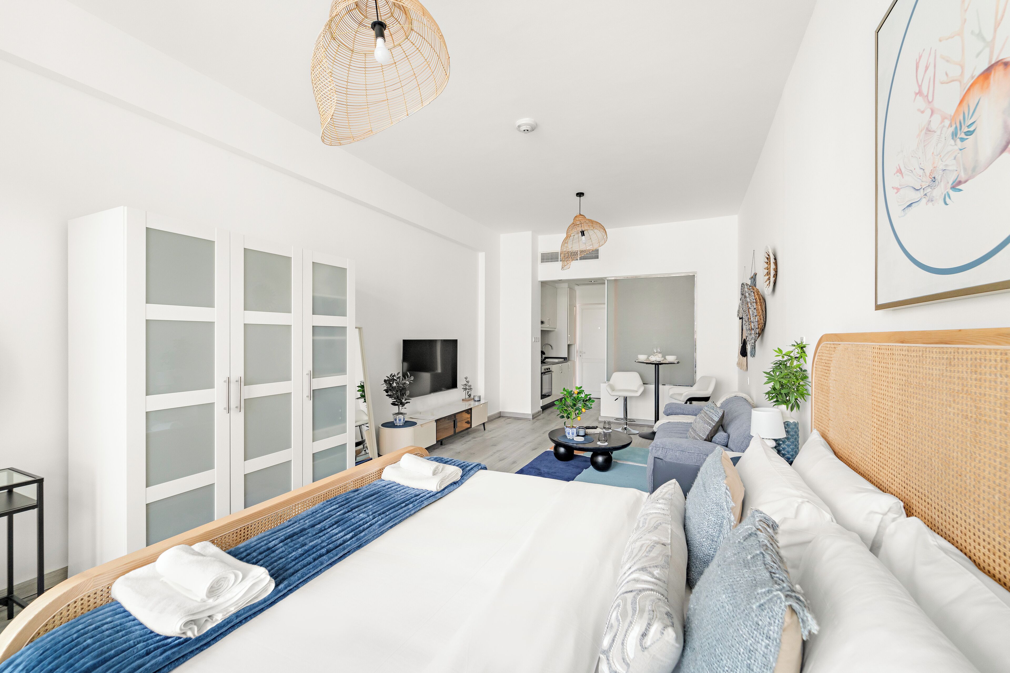 Une chambre d’hôtel moderne dotée d’un grand lit, d’un coin salon, d’une télévision et d’une kitchenette.