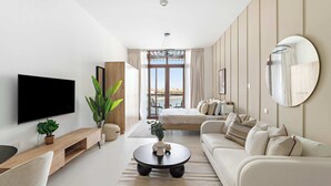 Un salon moderne avec un téléviseur à écran plat, une table basse ronde, un canapé et un grand miroir au mur.