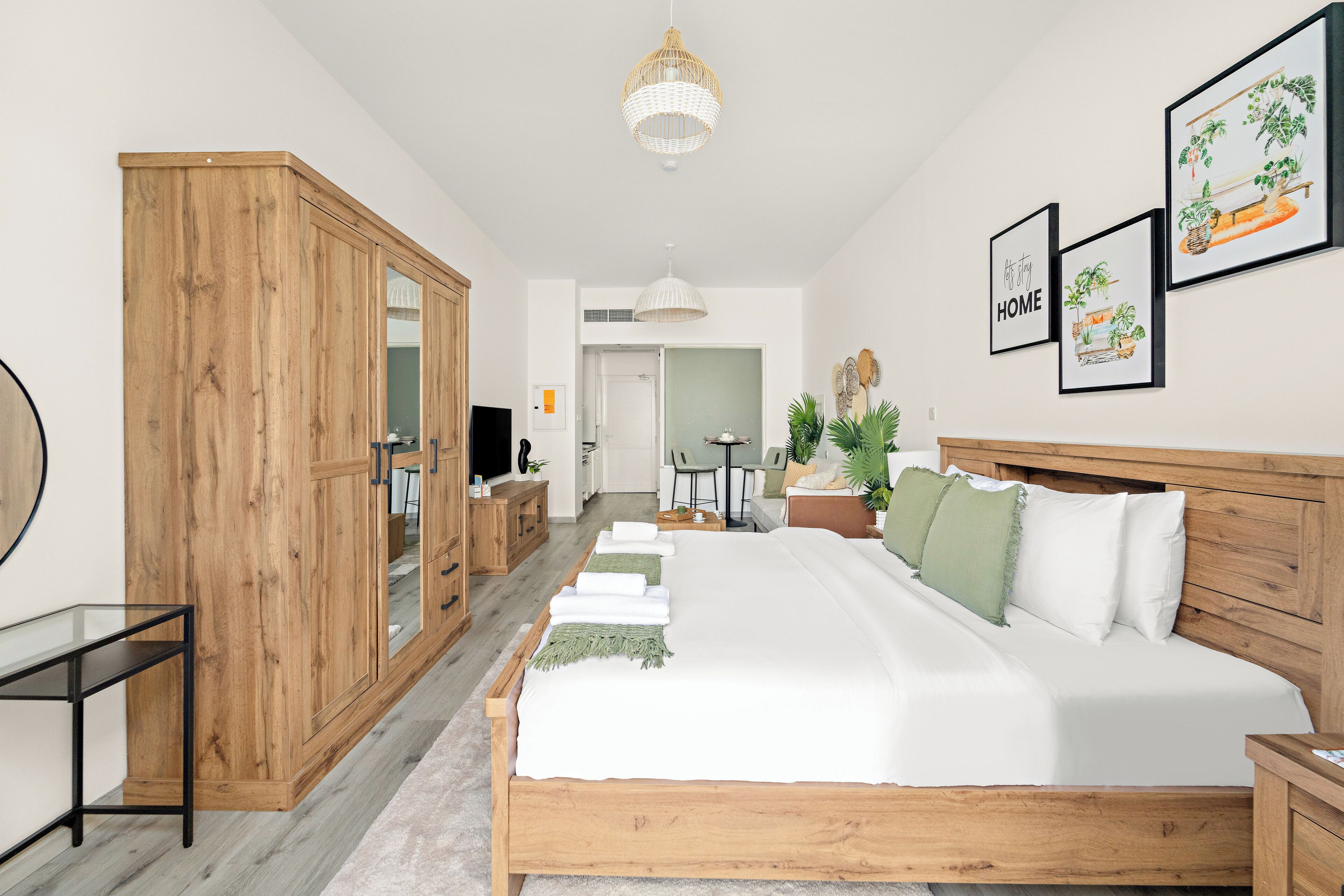 A bedroom with a large bed, wooden wardrobe, and a desk.