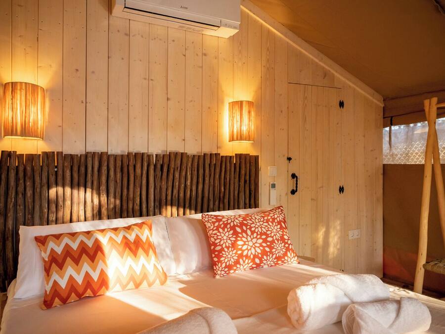 Quarto de madeira com uma cama, duas luminárias na parede e cabeceira de madeira.