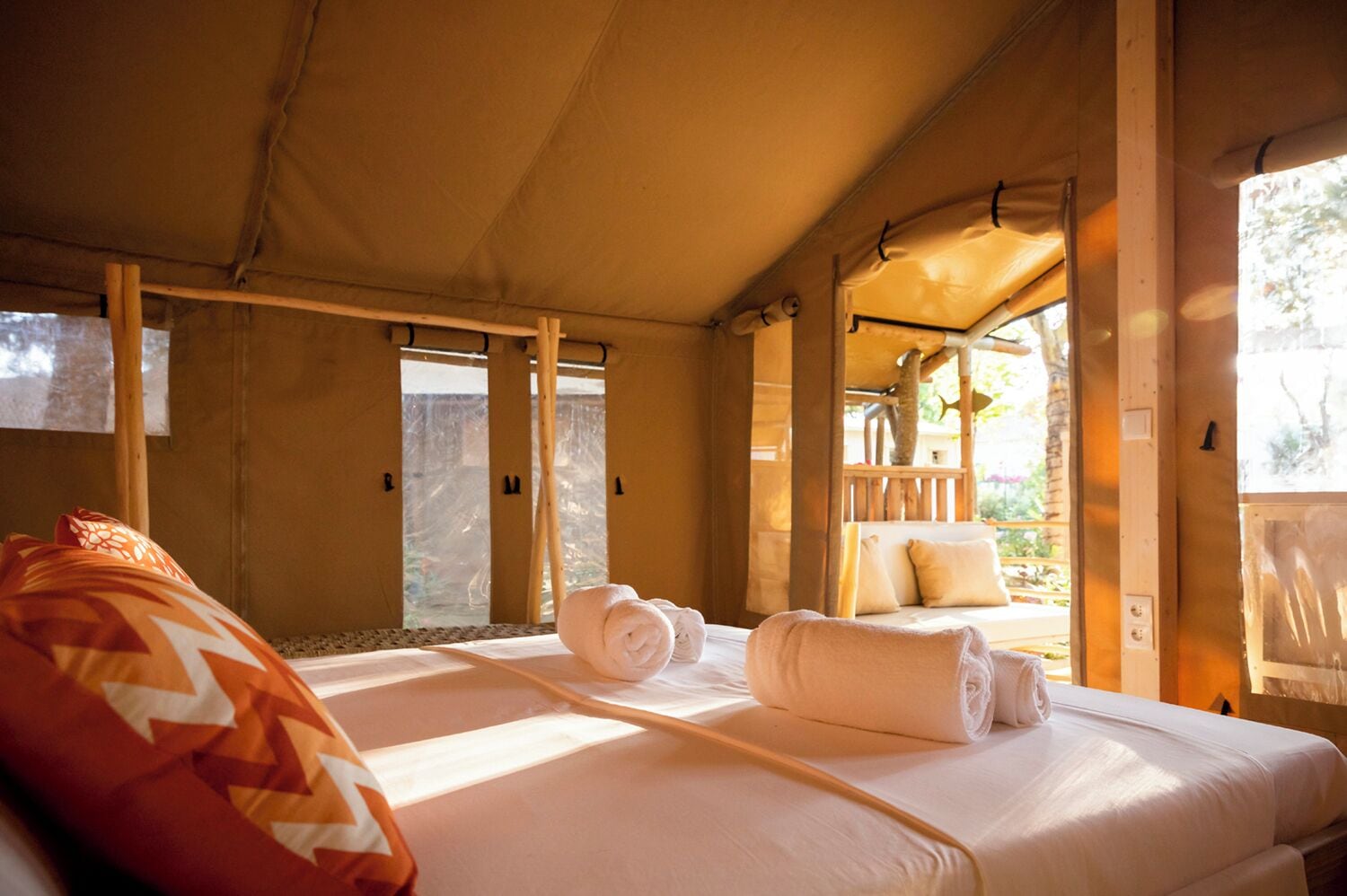 A tent-style room with two beds, a wooden ceiling, and a view of the outdoors.