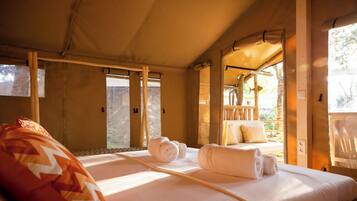 A tent-style room with two beds, a wooden ceiling, and a view of the outdoors.