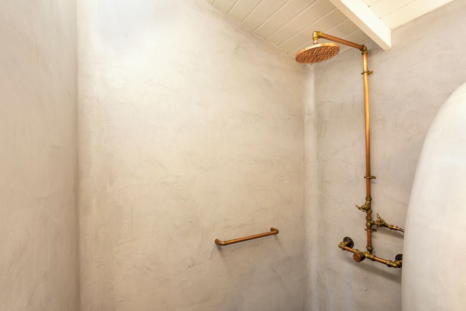 A shower with a handheld showerhead and a vertical pipe.