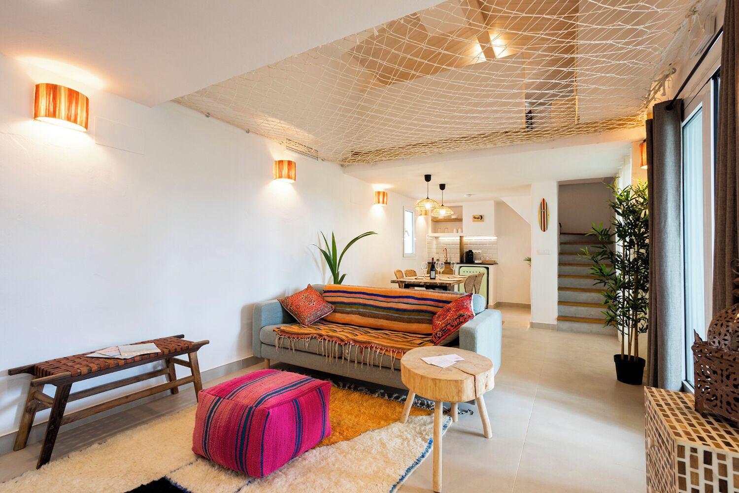 A modern living room with a sofa, a coffee table, and a wooden bench. There is a staircase leading to an upper level.