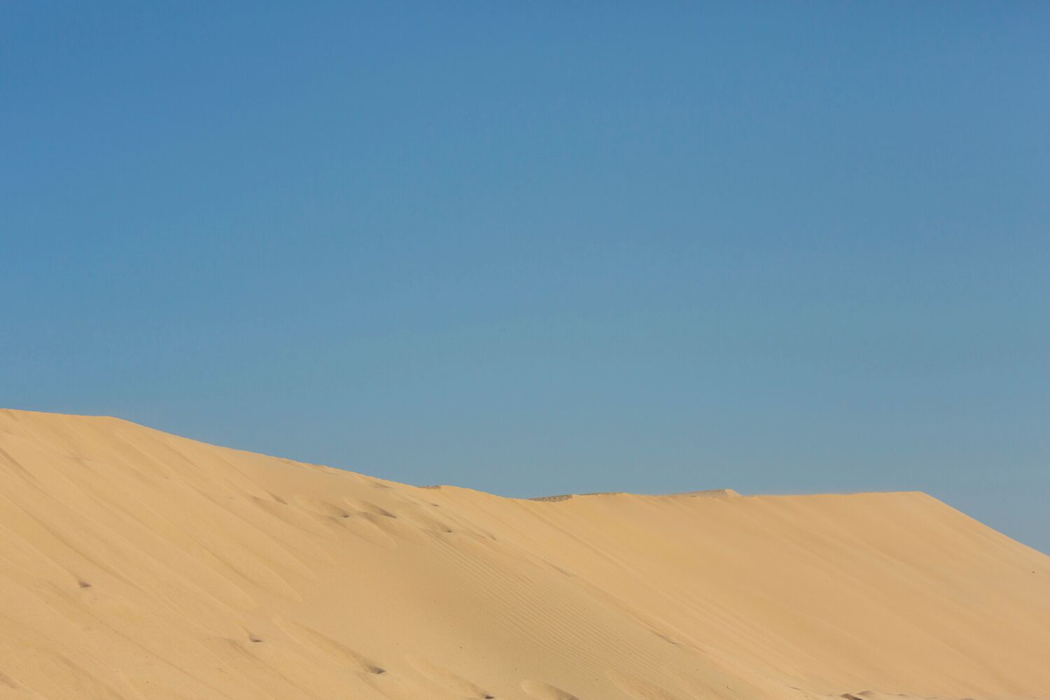 A clear sky above a sandy landscape.