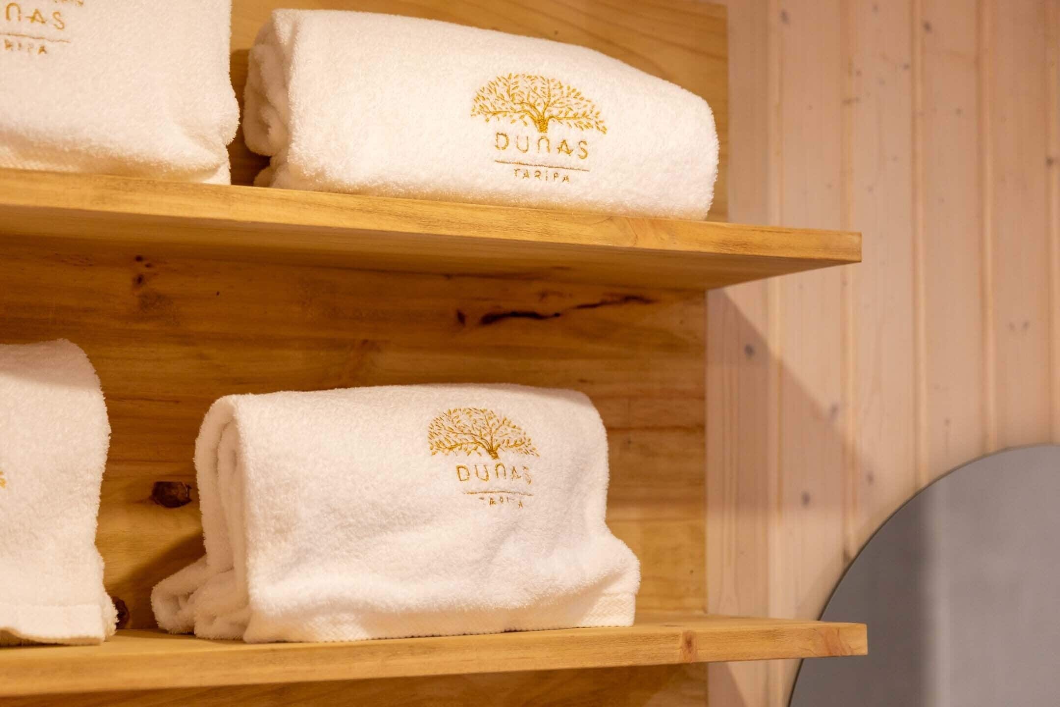 Ein Holzregal mit ordentlich gefalteten weißen Handtüchern, einem Baum-Logo und Text.