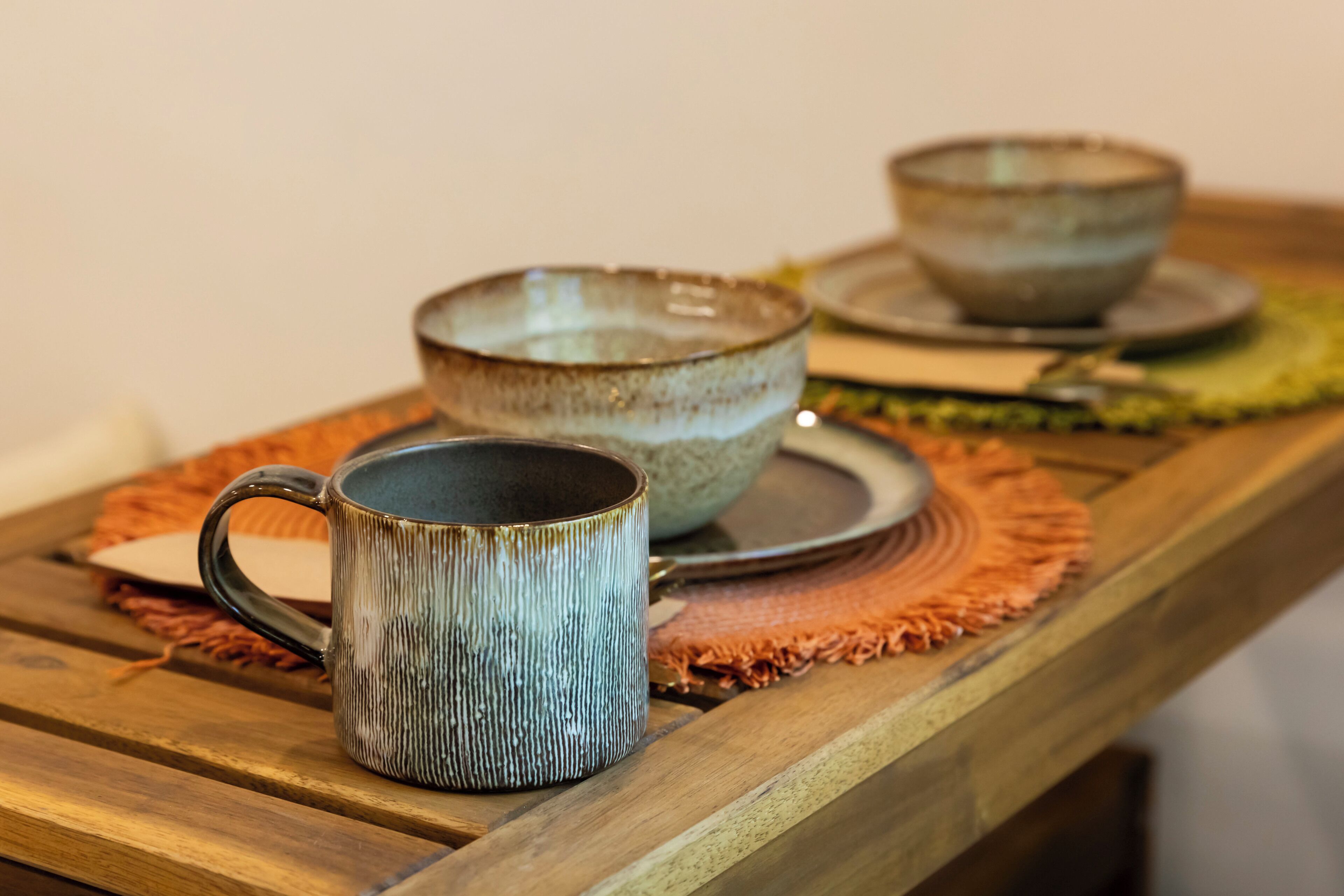 A wooden table with ceramic bowls and a mug.