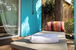 A sunlit outdoor seating area with a bench, a colorful striped pillow, and a blue door. - Dunas Tarifa (Tarifa)