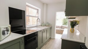 A modern kitchen with a built-in microwave, a toaster, and a sink. - Sole Bay Cottage (Lowestoft)