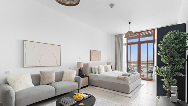 Un salon moderne avec un canapé, une table basse et un lit. Une grande fenêtre offre une vue sur la ville.