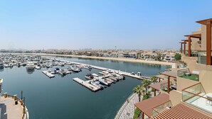 Un port de plaisance où sont amarrés de nombreux bateaux, un ciel dégagé et un bâtiment moderne doté d’une terrasse sur le toit.