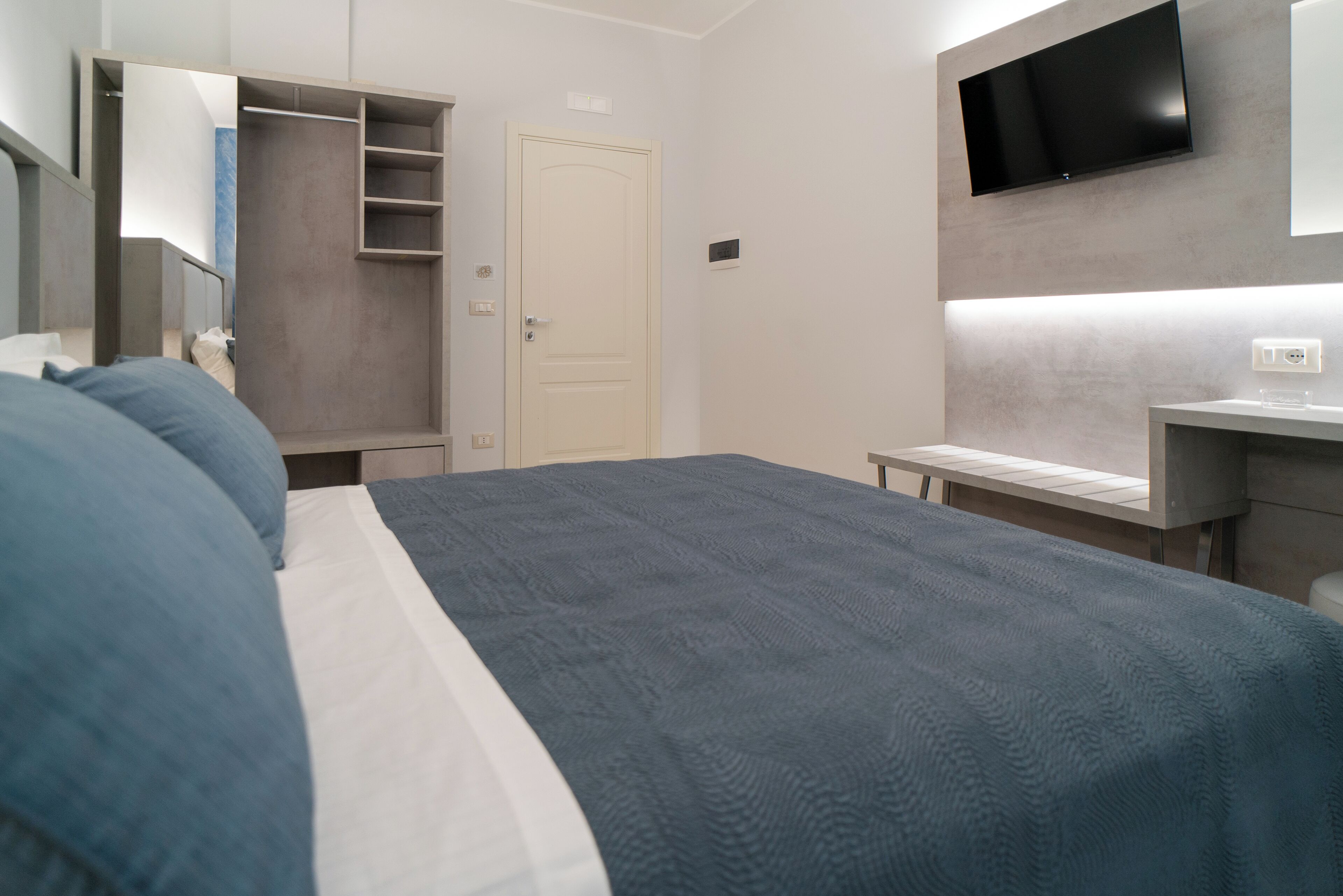 Un dormitorio moderno con cama, armario, televisión y zona de baño.