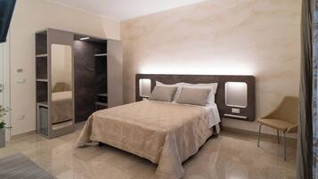 A modern bedroom with a large bed, a built-in wardrobe, and a seating area.