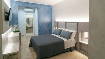 A modern bedroom with a bed, bedside table, and a TV mounted on the wall.