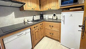 A compact kitchen with wooden cabinets, a Bosch dishwasher, a microwave, and a toaster. - Apartment with balcony, parking and pets allowed in Chamonix (Chamonix-Mont-Blanc)