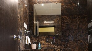 A modern bathroom with a marble backsplash, a sink, a mirror, and a towel rack. - Hotel Galaxy Deluxe (Jalna)