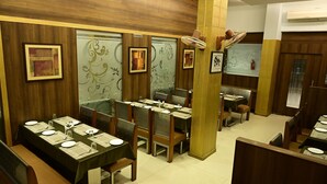 A restaurant with wooden paneling, framed artwork, and tables set for dining. - Hotel Galaxy Deluxe (Jalna)