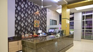 A reception area with a marble counter, a ceiling fan, and a chandelier. - Hotel Galaxy Deluxe (Jalna)