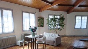 A living room with a white sofa, a dining table with chairs, a potted plant, and a fireplace. - Hôtel Le Cheval Blanc (Saint-Maixent-l'Ecole)