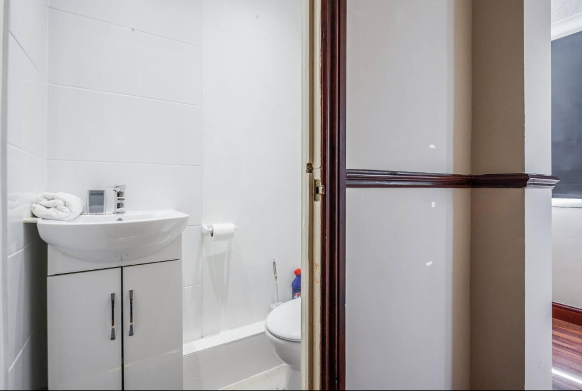 A bathroom with a white sink, toilet, and shower area.