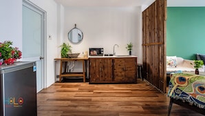 A compact kitchen with a sink, microwave, and wooden cabinets. - HOLO BEN THANH SAIGON SERVICED HOMESTAY (Ho Chi Minh City)