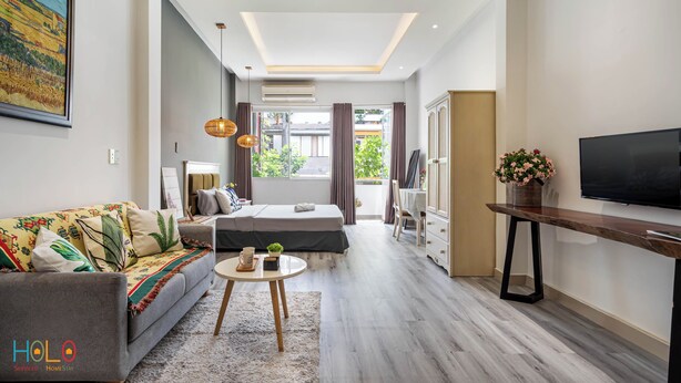 A modern living room with a sofa, a bed, a TV, and a dining area. - HOLO BEN THANH SAIGON SERVICED HOMESTAY (Ho Chi Minh City)
