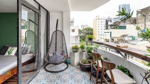 A balcony with a hanging chair, potted plants, and a view of the cityscape. - HOLO BEN THANH SAIGON SERVICED HOMESTAY (Ho Chi Minh City)