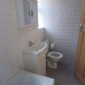 A bathroom with a white sink, toilet, and bathtub. - Lovely 2-bed Apartment in Bridlington (Bridlington)
