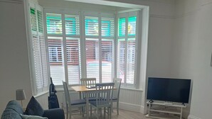 Una sala de estar con un sofá, un televisor y una mesa de comedor con sillas.