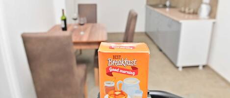 A breakfast box labeled "Best Breakfast Good morning" in a modern kitchen with a dining table and chairs.