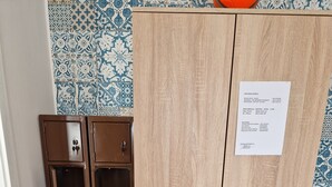 A wooden wardrobe with two doors and a small shelf, a pair of brown cabinets, and a patterned wall.