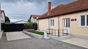 A residential building with a tiled roof, a small garden, and a gravel driveway.