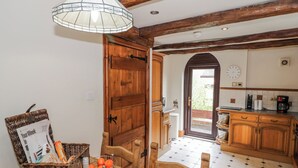 A kitchen with wooden cabinets, a dining table, a wicker basket, and a hanging light fixture.