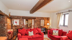 A cozy living room with red sofas, a wooden coffee table, and a brick fireplace.