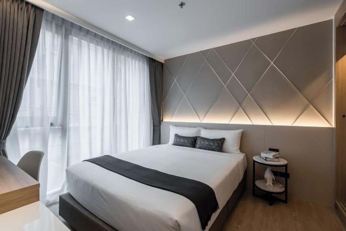 Een moderne hotelkamer met een groot bed, een nachtkastje en een stoel.