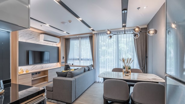 A modern living room with a sofa, TV, and dining area.
